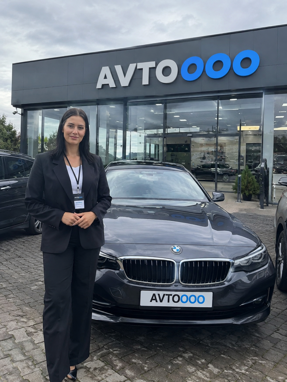 Клиент AVTOOOO у нового автомобиля перед зданием автосалона